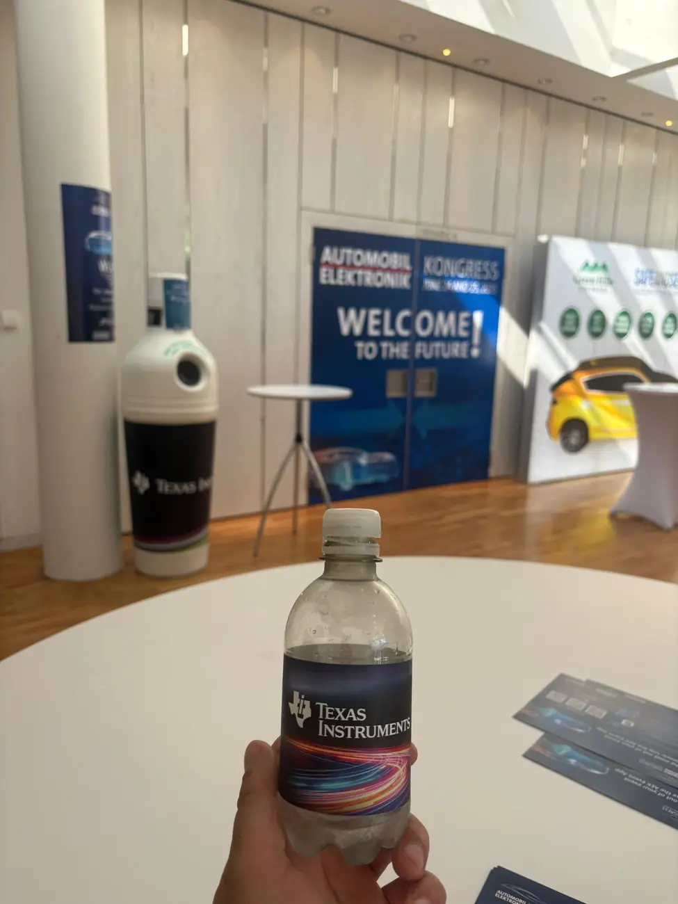 Pfandbehälter mit Unternehmensbranding im Foyer einer Veranstaltung, Besucher mit Pfandflasche im Vordergrund