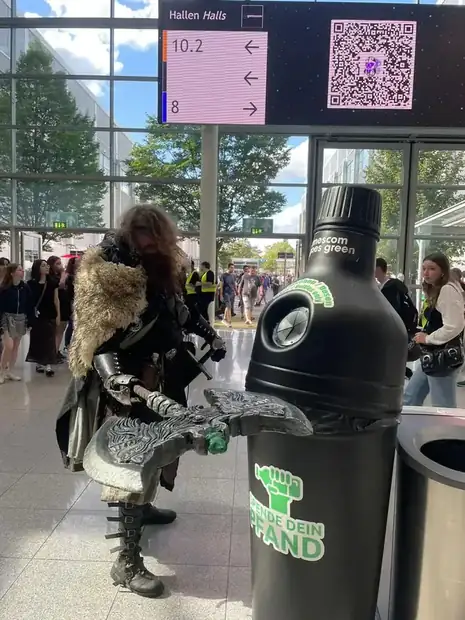 Pfandbehälter am Halleneingang einer Messe unter der Hallenbeschilderung